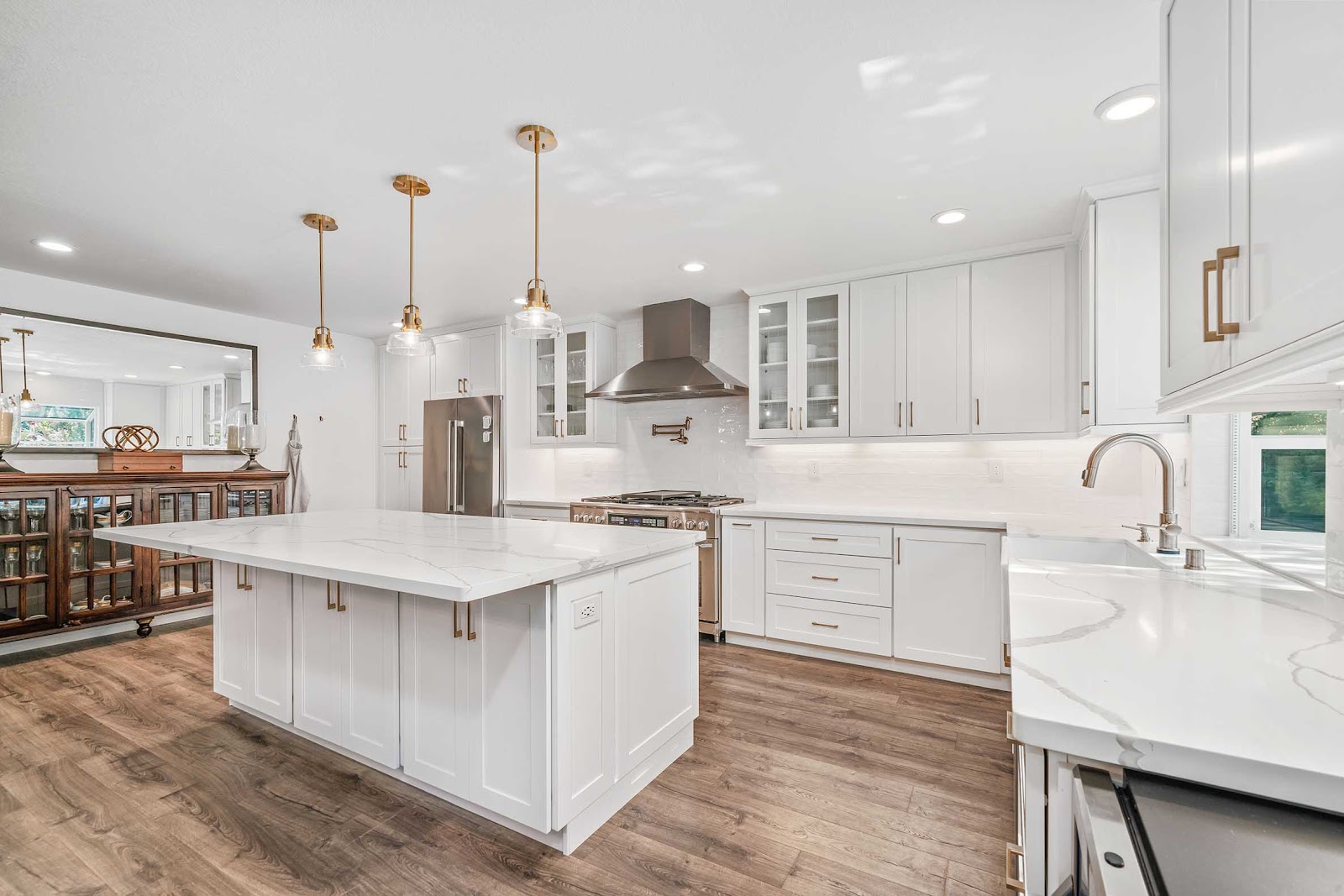 Bright white kitchen with an island, flooring and pendant lights